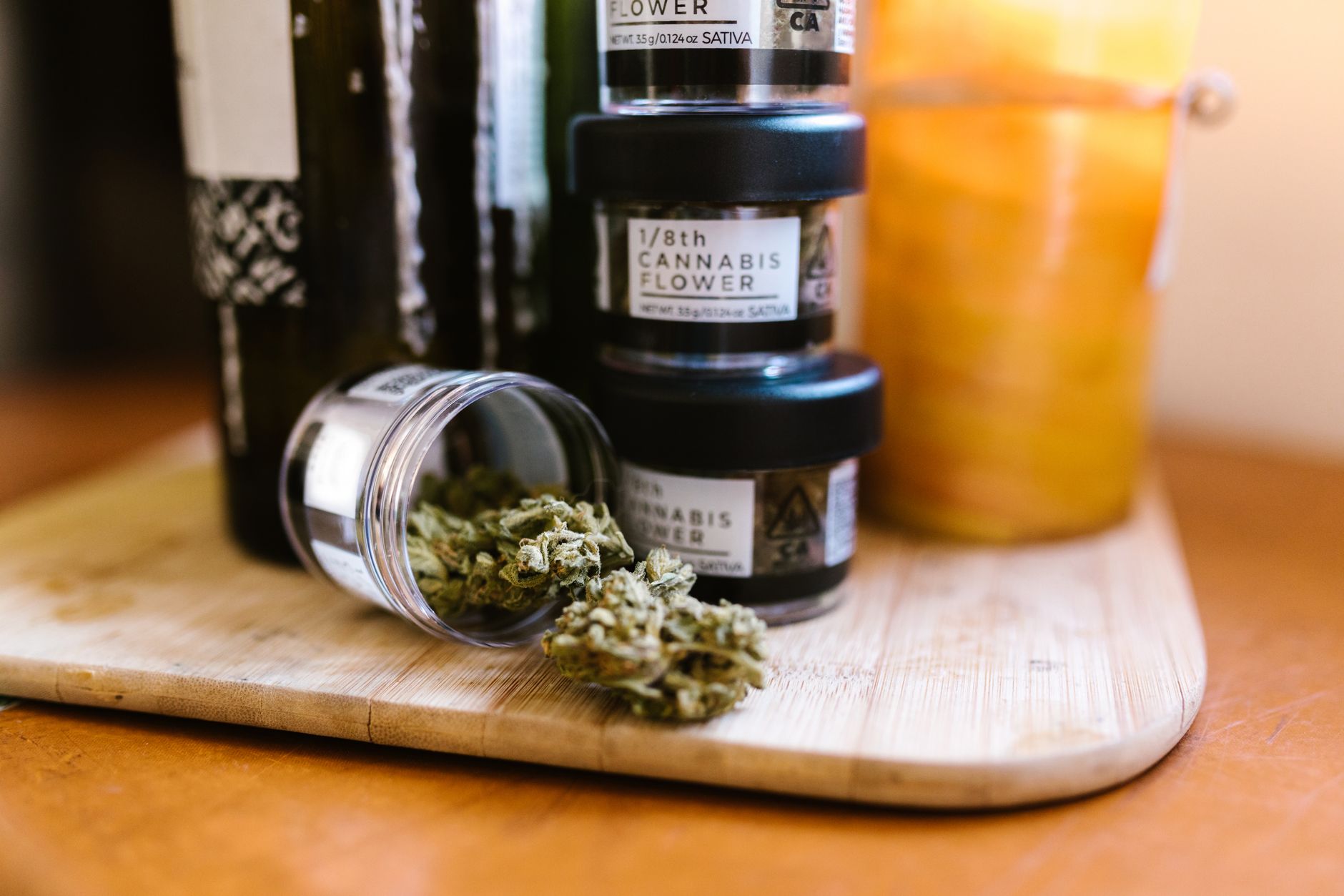 Cogollos de cannabis en tarros de cristal sobre una tabla de madera en interior con luz suave.