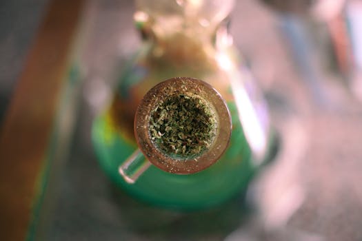 Imagen detallada de cannabis molido en una pipa de agua de cristal, destacando su textura intrincada.